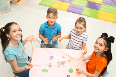 Photo of Happy children playing with slime at table indoors, above view