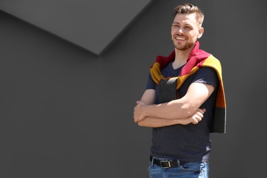 Photo of Portrait of young man in stylish outfit near grey wall