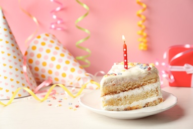 Photo of Slice of delicious birthday cake with candle on table