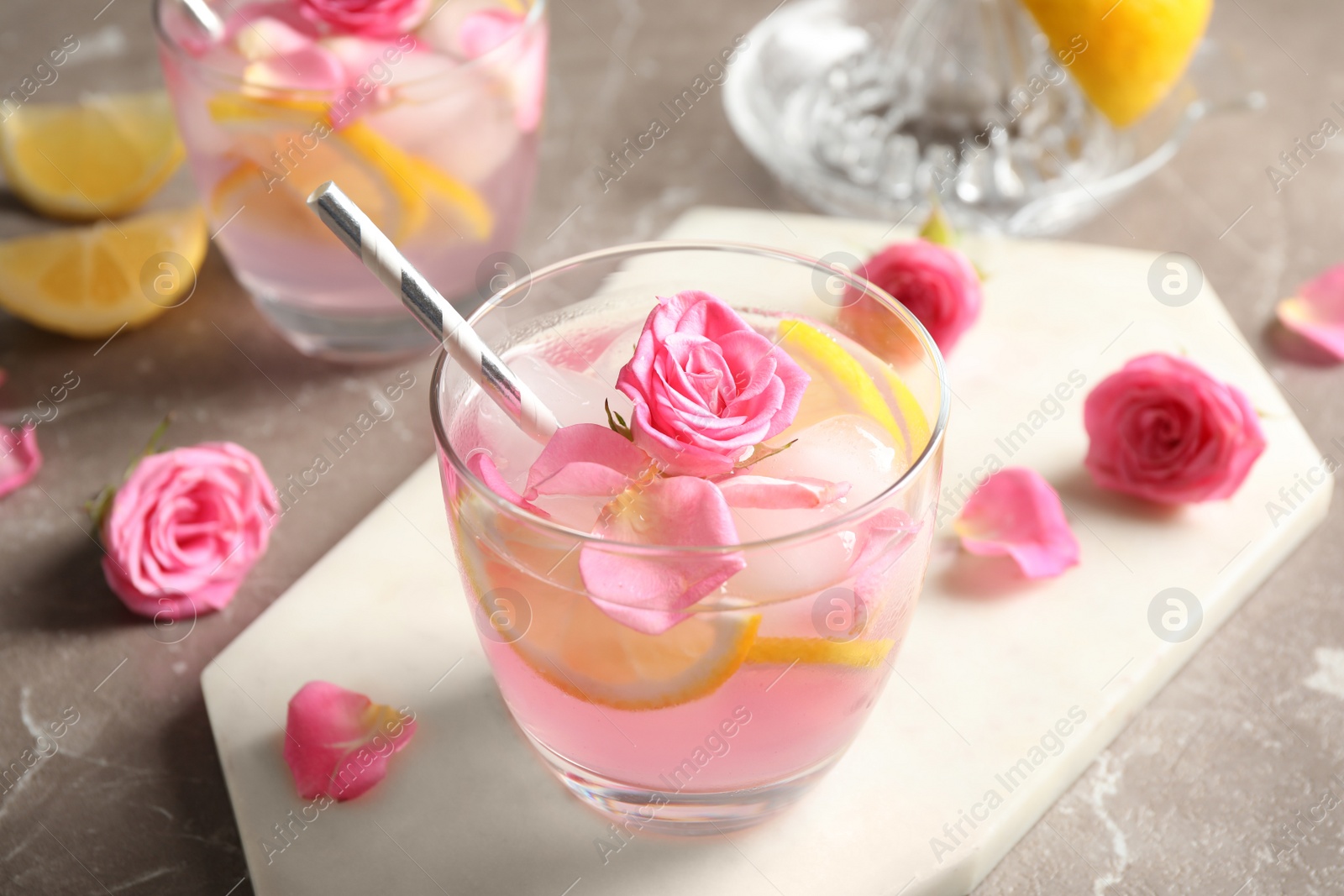 Photo of Delicious refreshing drink with lemon and roses on marble table