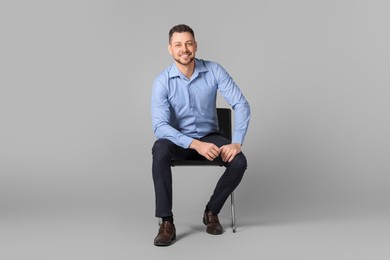 Photo of Handsome man sitting in office chair on grey background