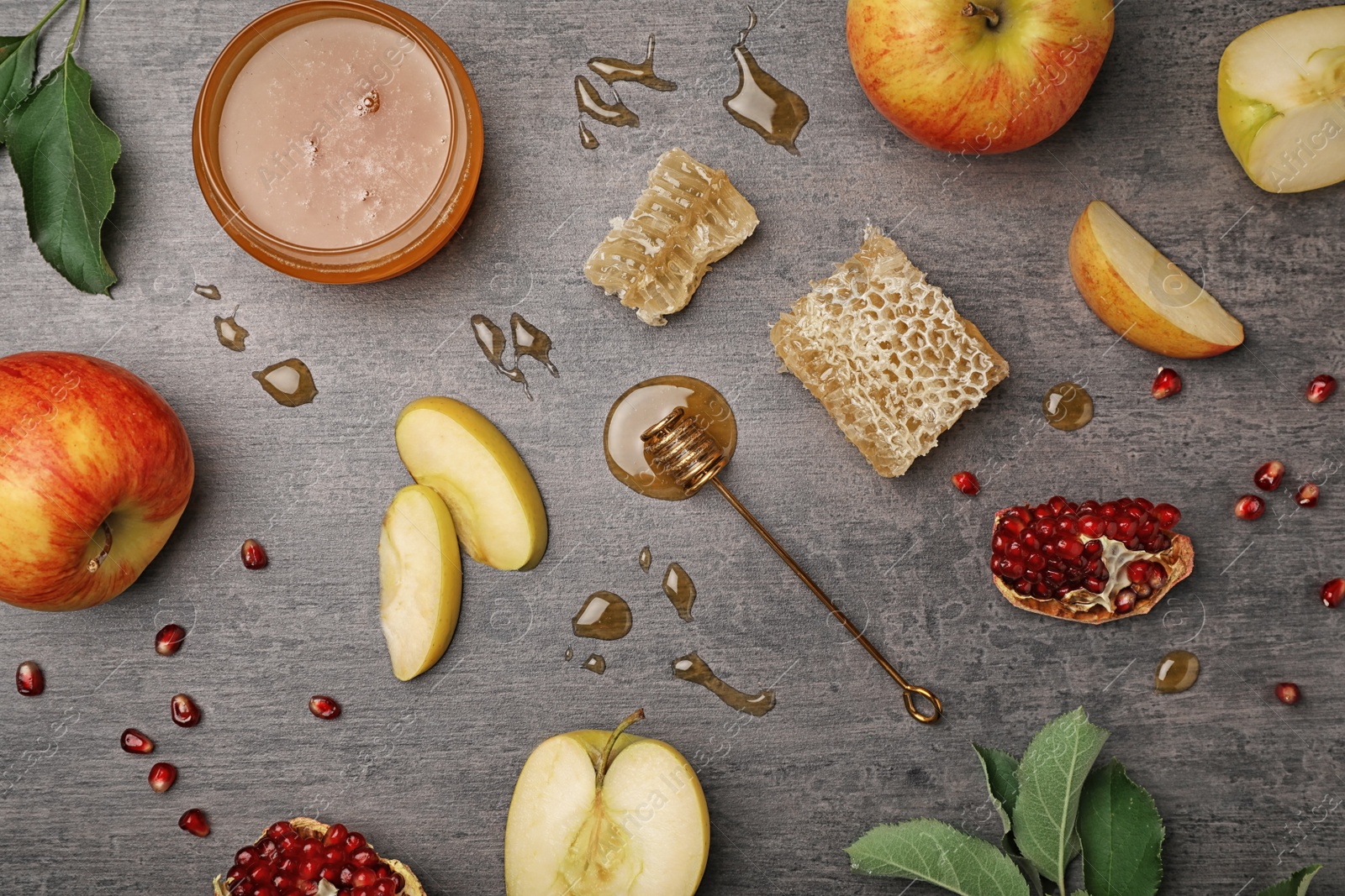 Photo of Flat lay composition with jar of honey, dipper, apples and pomegranate on dark background. Rosh Hashanah holiday