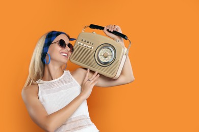 Photo of Happy hippie woman with retro radio receiver on orange background. Space for text