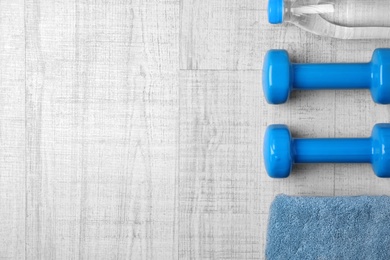 Photo of Flat lay composition with dumbbells and space for text on wooden background. Home fitness