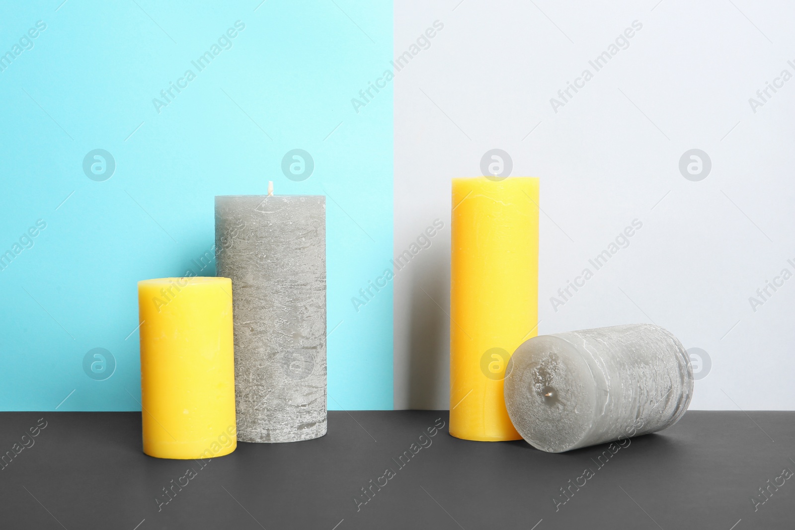 Photo of Decorative wax candles on table against color background