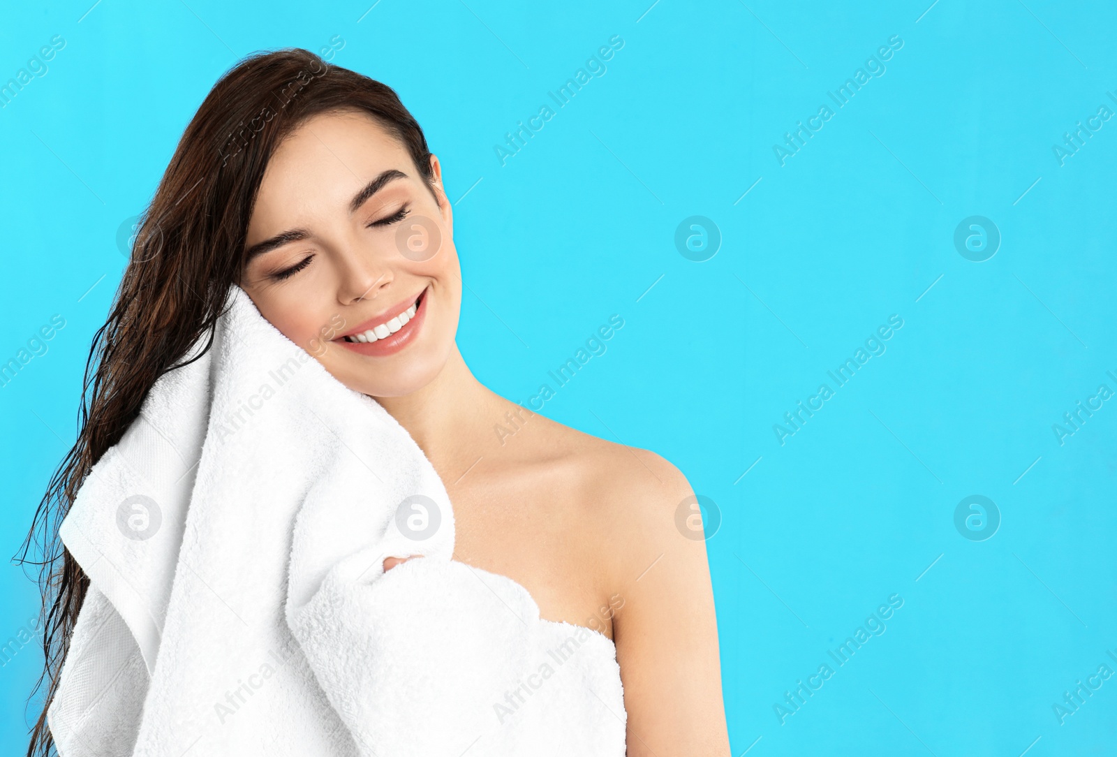 Photo of Young woman wiping face with towel on light blue background. Space for text