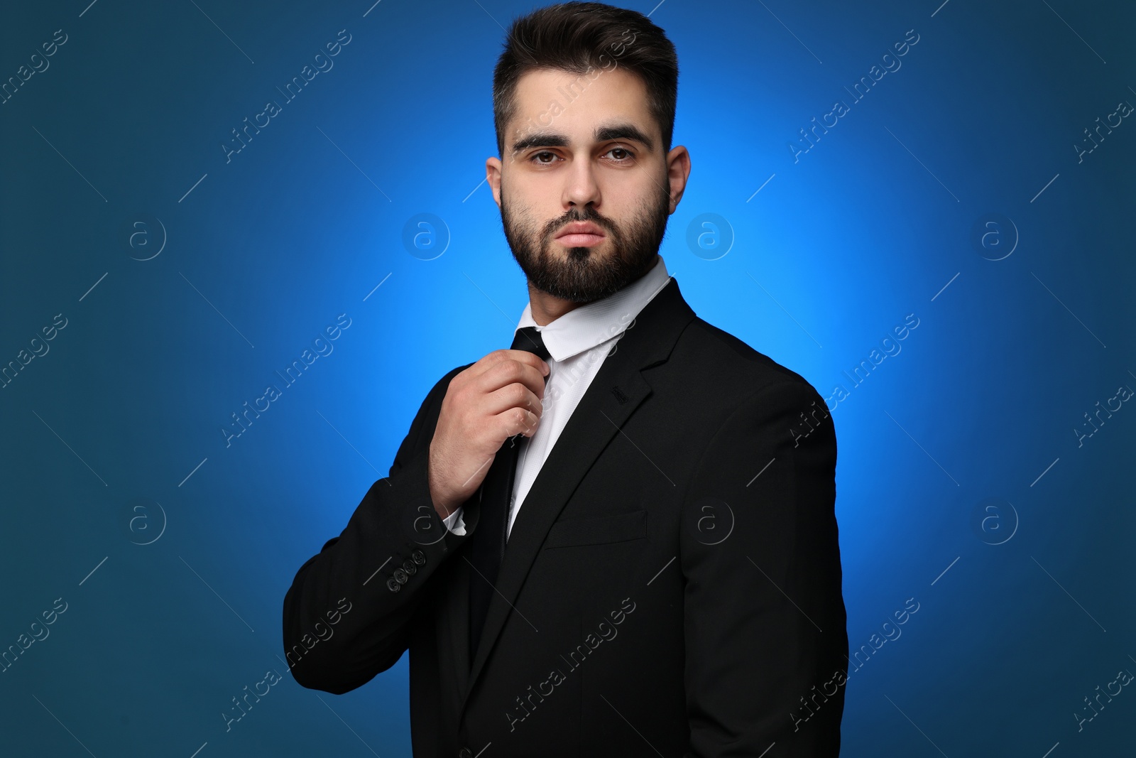 Photo of Handsome businessman in suit and necktie on blue background