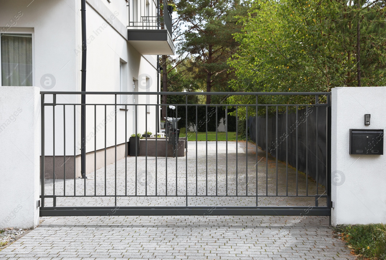 Photo of Closed metal gates near beautiful trees and building outdoors