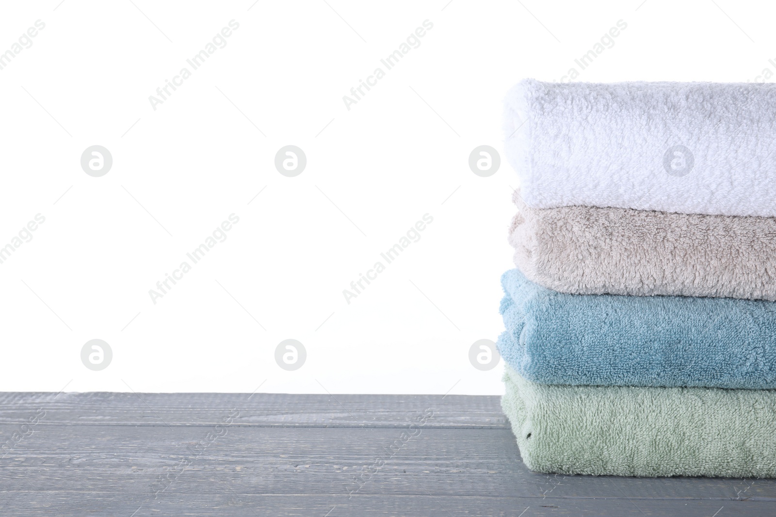 Photo of Fresh towels on grey wooden table against white background. Space for text