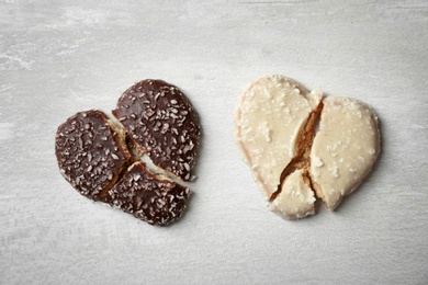 Photo of Broken heart shaped cookies on gray background, top view. Relationship problems