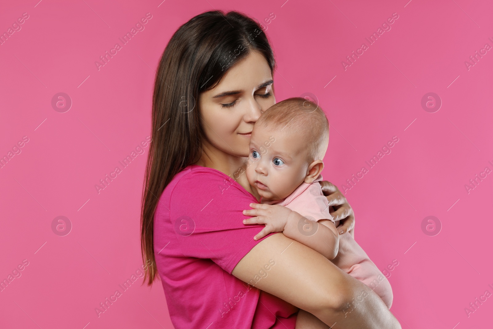 Photo of Beautiful mother with her cute baby on pink background