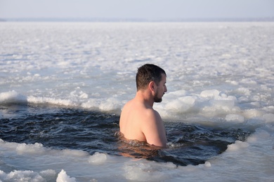 Photo of MYKOLAIV, UKRAINE - JANUARY 06, 2021: Man immersing in icy water on winter day