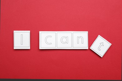 Photo of Motivation concept. Changing phrase from I Can't into I Can by removing paper with letter T on red background, flat lay