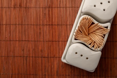 Holder with salt, pepper and toothpicks on bamboo mat, top view. Space for text