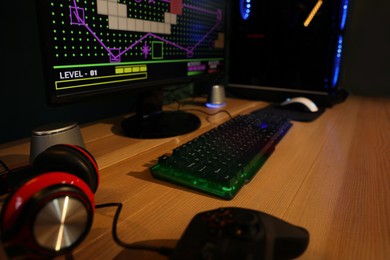 RGB keyboard, modern computer and headphones on wooden table indoors