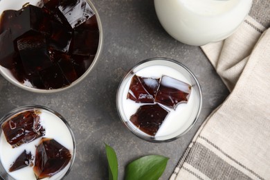 Photo of Glasses of milk with delicious grass jelly on grey table, flat lay