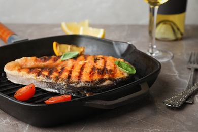 Frying pan with tasty salmon steak on table