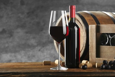 Photo of Winemaking. Composition with tasty wine and barrel on wooden table against gray background, space for text