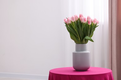 Beautiful bouquet of fresh pink tulips on table indoors. Space for text