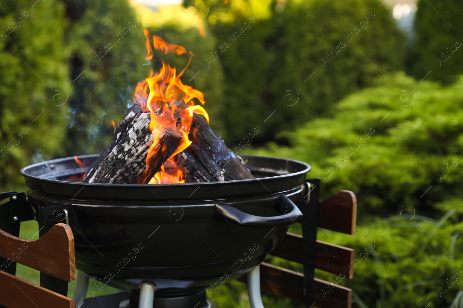 Photo of Portable barbecue grill with fire flames outdoors, closeup. Space for text
