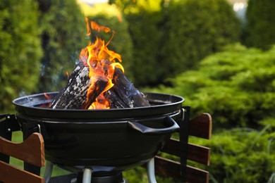 Photo of Portable barbecue grill with fire flames outdoors, closeup. Space for text