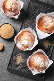 Photo of Delicious muffins and sugar on grey table, flat lay