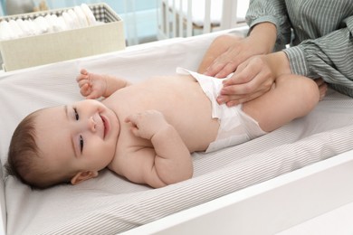 Photo of Mother changing baby's diaper on table at home