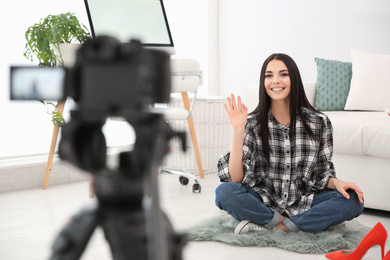 Photo of Young blogger recording video on camera indoors