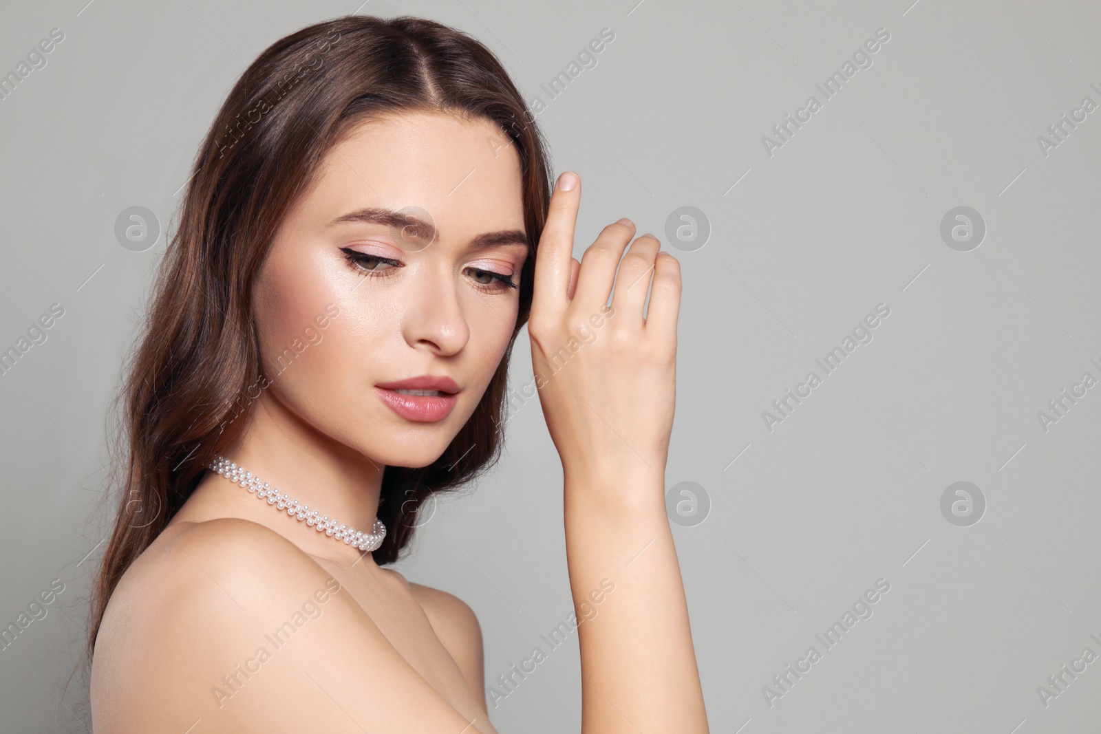 Photo of Young woman wearing elegant pearl necklace on grey background, space for text