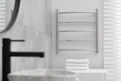 Modern heated towel rail on wall in bathroom