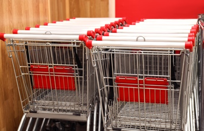 Photo of Many empty shopping carts in supermarket, closeup