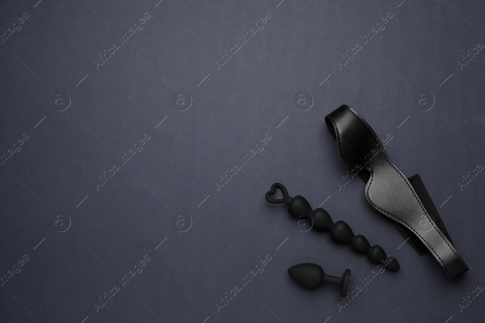 Photo of Sex toys and leather blindfold on black background, flat lay. Space for text