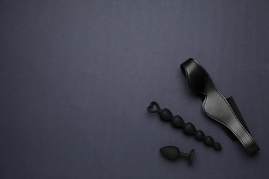 Photo of Sex toys and leather blindfold on black background, flat lay. Space for text