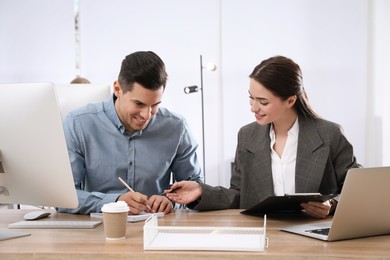 Businesswoman helping intern with work in office