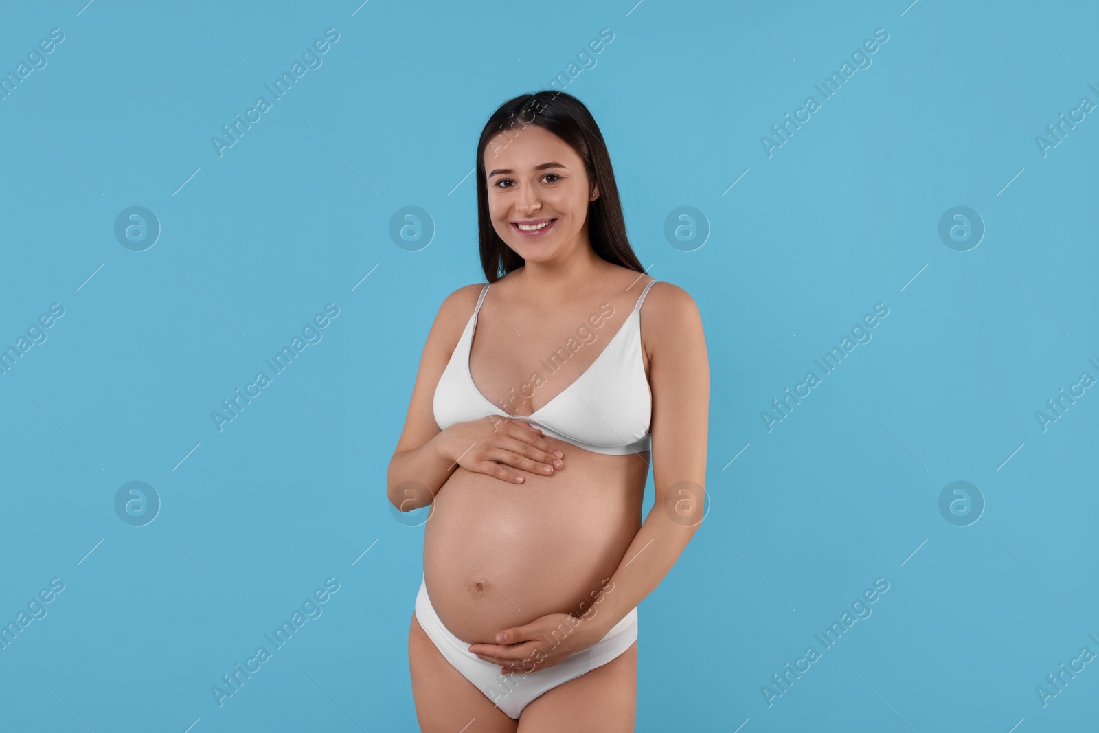 Photo of Beautiful pregnant woman in stylish comfortable underwear on light blue background