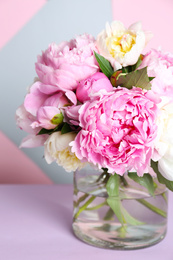 Photo of Bouquet of beautiful peonies in vase on lilac table