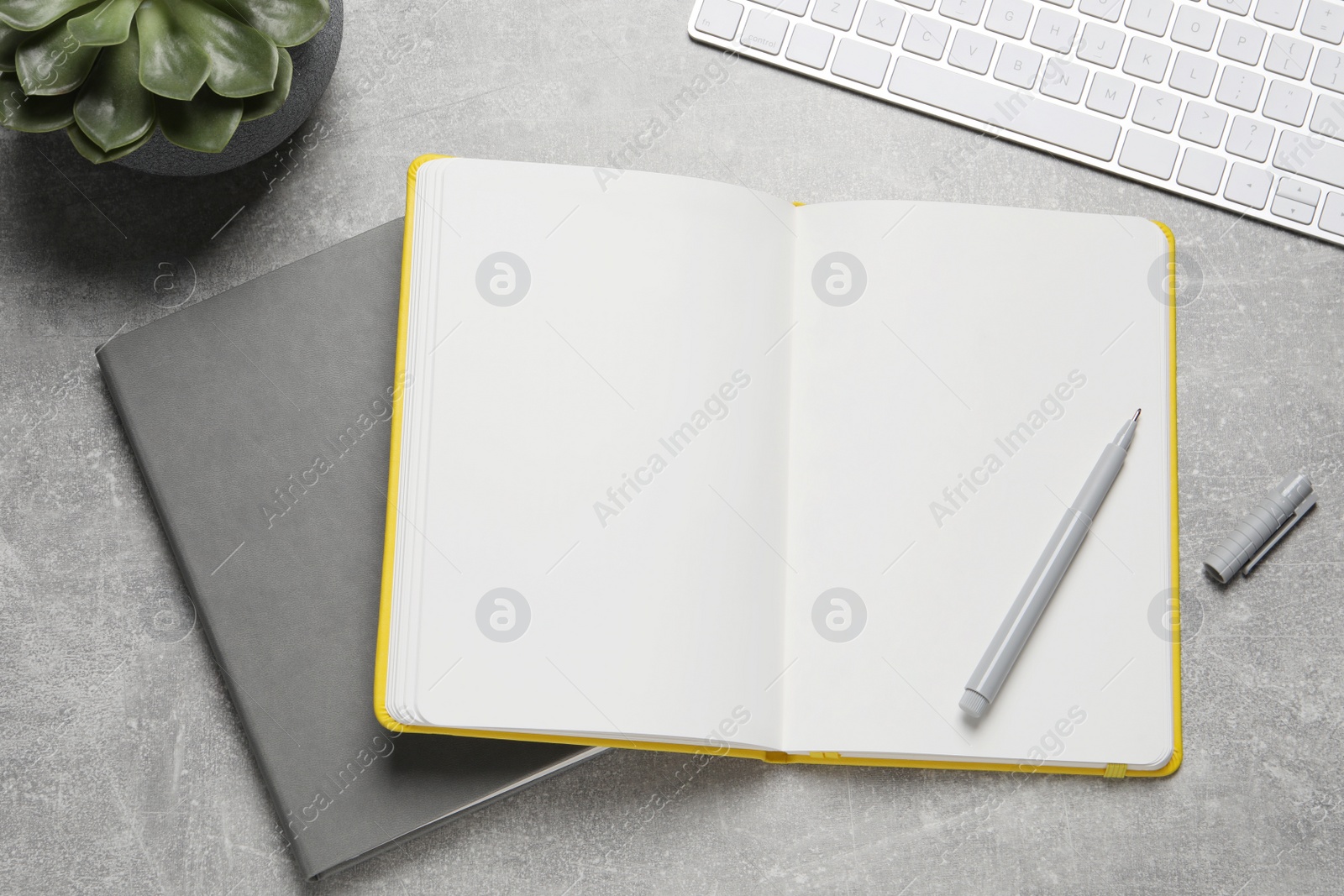 Photo of Notebooks, pen and keyboard on light grey table, flat lay