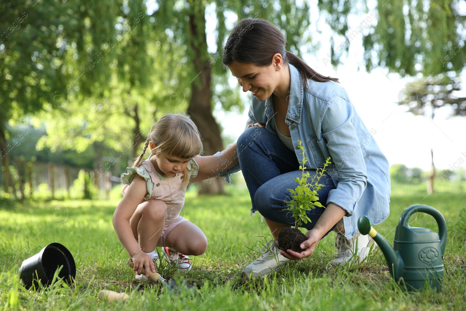 Photo of Mother and her daughter planting tree together in garden