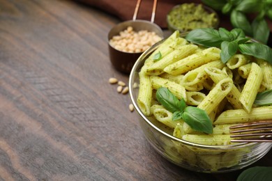 Photo of Delicious pasta with pesto sauce and basil on wooden table, closeup. Space for text