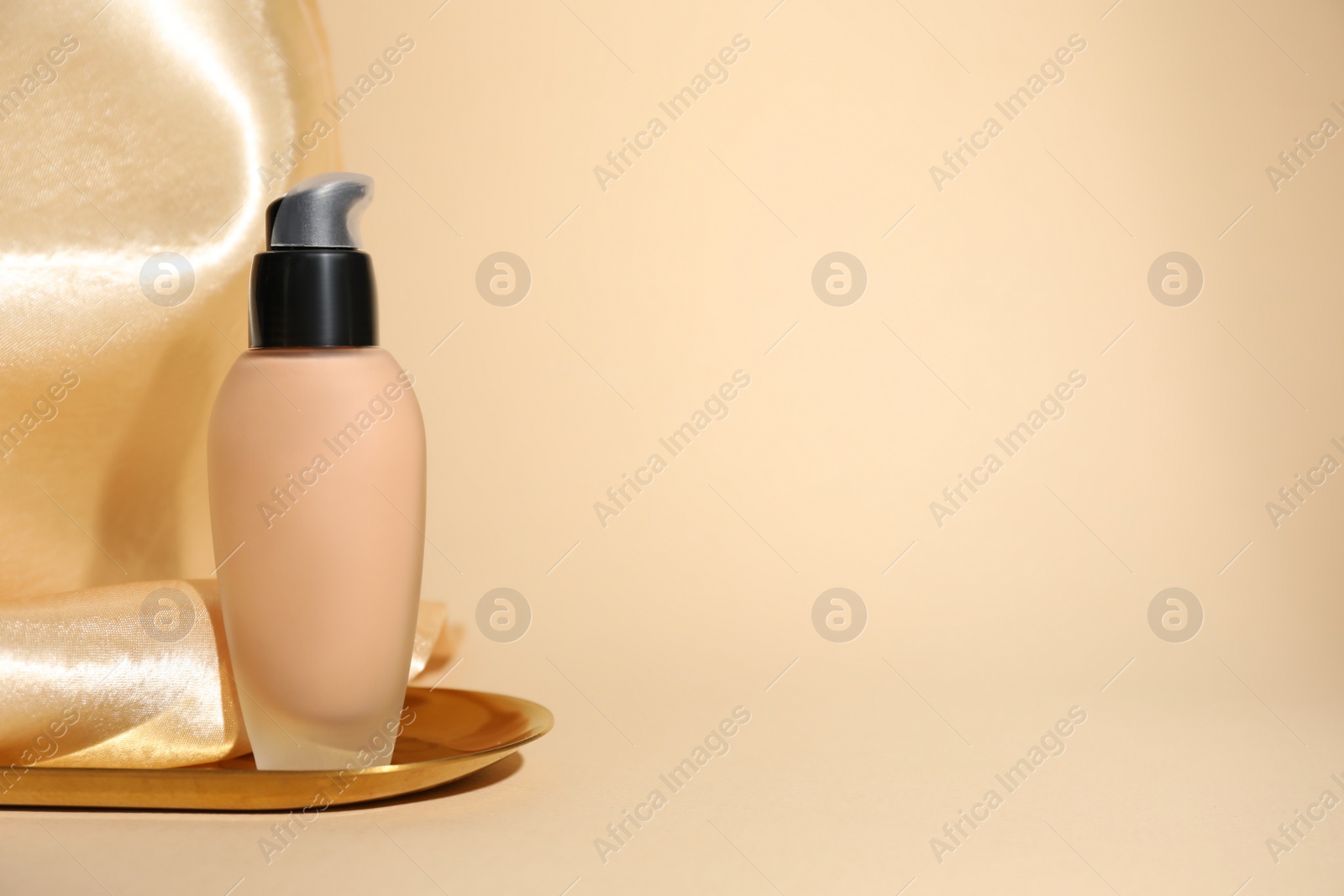 Photo of Fluid foundation on beige background, space for text