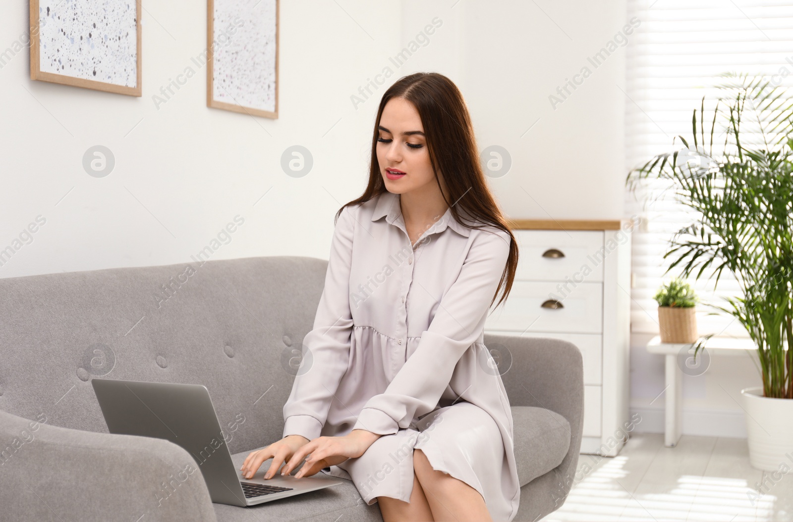 Photo of Young woman working with modern laptop on sofa