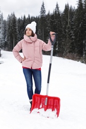 Woman with shovel for cleaning snow outdoors