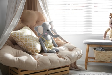 Photo of Beautiful baby room interior with comfortable armchair and bench near window