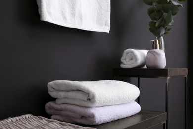 Photo of Clean soft towels on stand near black wall