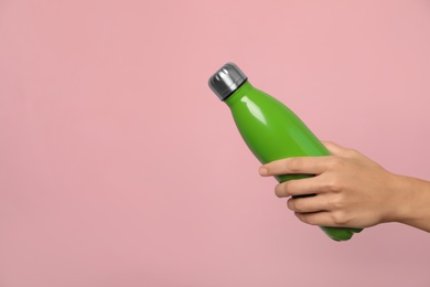 Woman holding modern green thermos on pink background, closeup. Space for text
