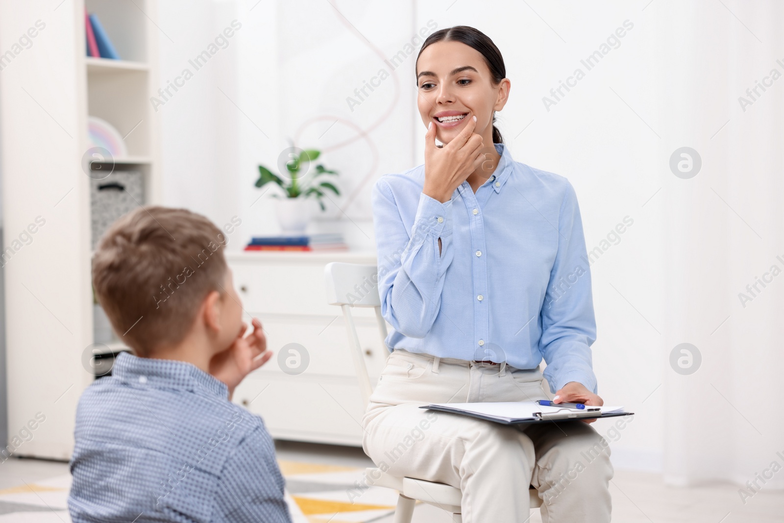 Photo of Dyslexia treatment. Speech therapist working with boy in room