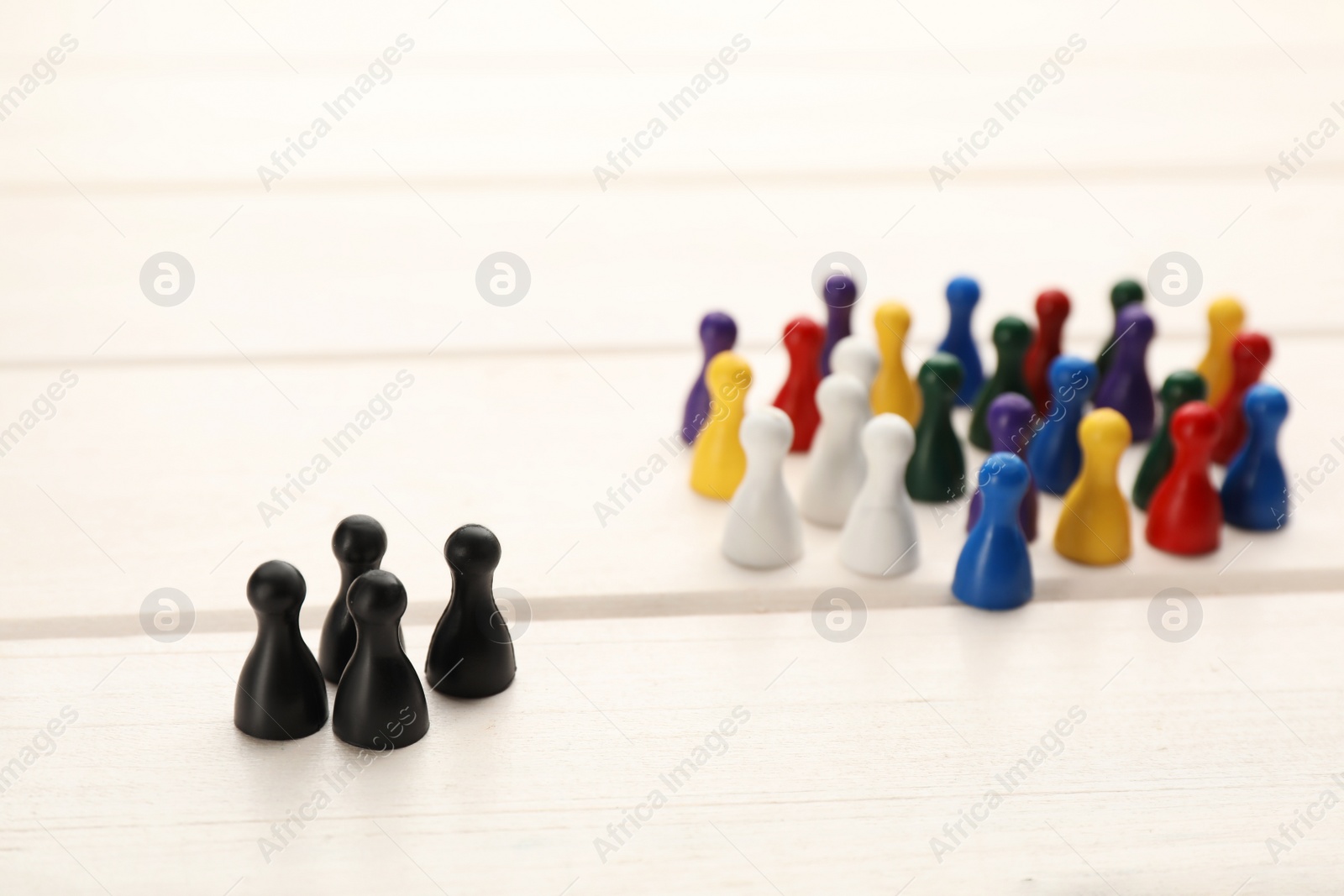 Photo of Colorful game pieces on white wooden table. Racism concept