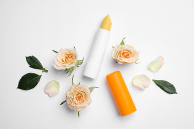 Hygienic lipstick and rose flowers on white background, top view