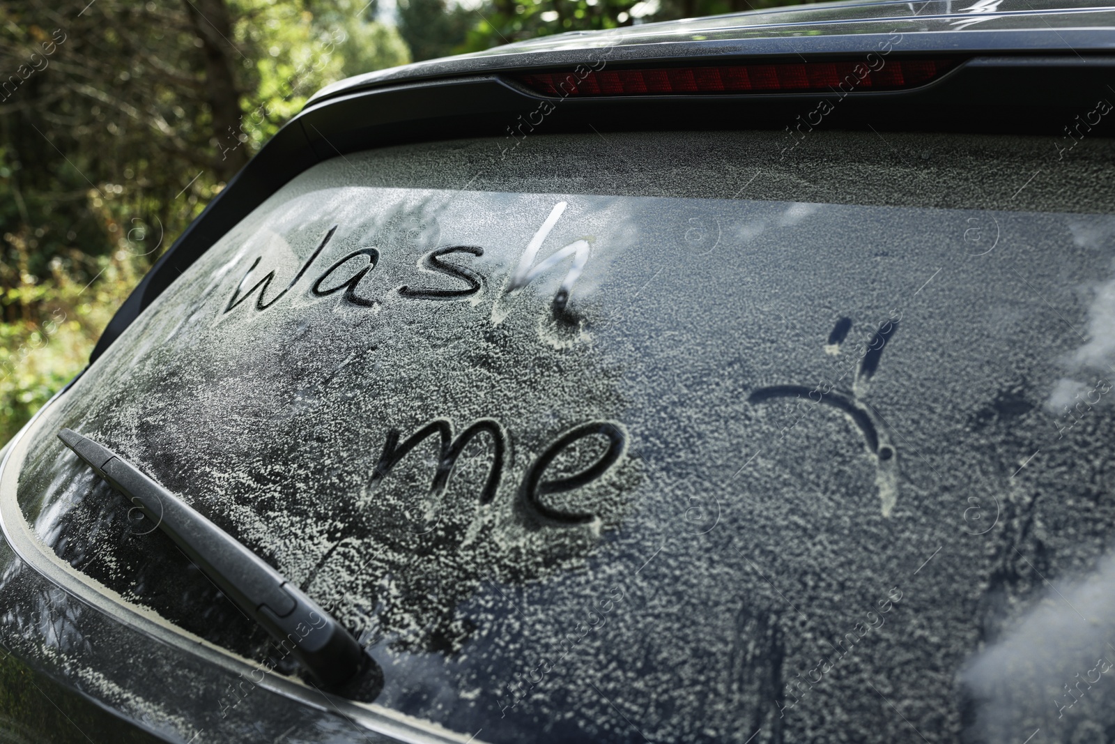 Photo of Phrase Wash me written on dirty car window outdoors, closeup