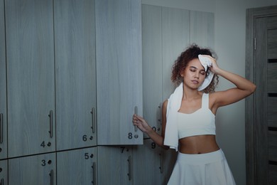 Beautiful tired African American woman after training in locker room